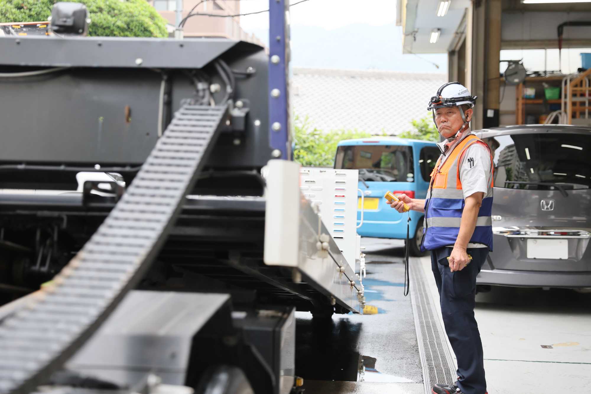 ヘルメットと反射ベストを身に着けた男性作業員が重機の前に立っている場面